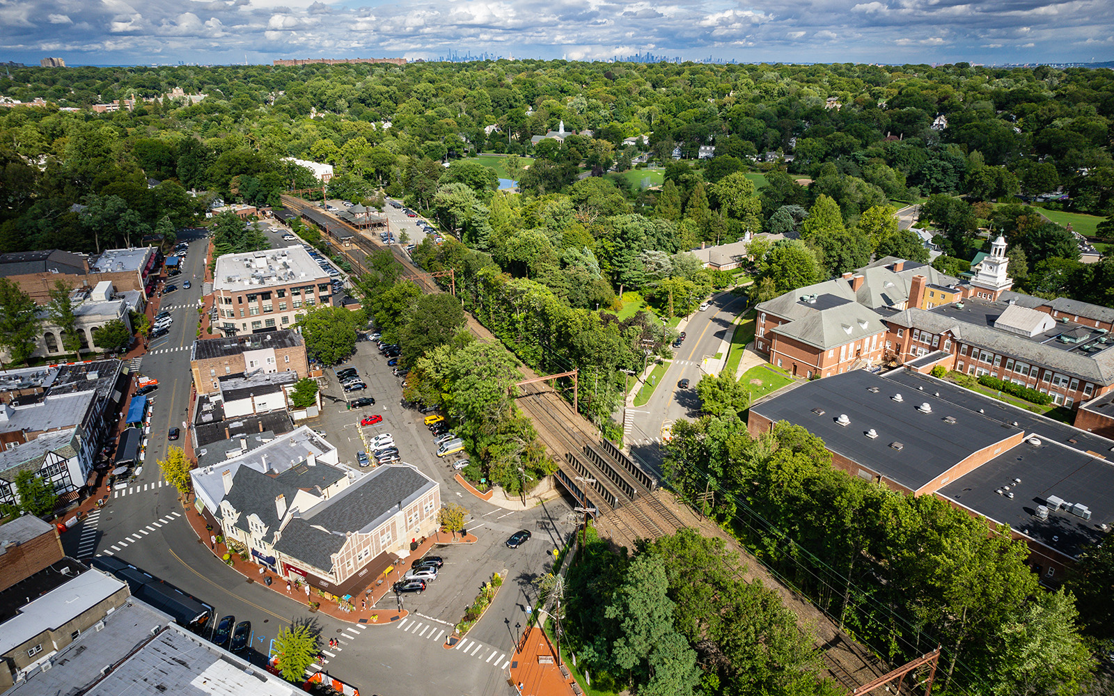 Aerial view of a suburban neighborhood with houses, roads, and greenery under a partly cloudy sky.